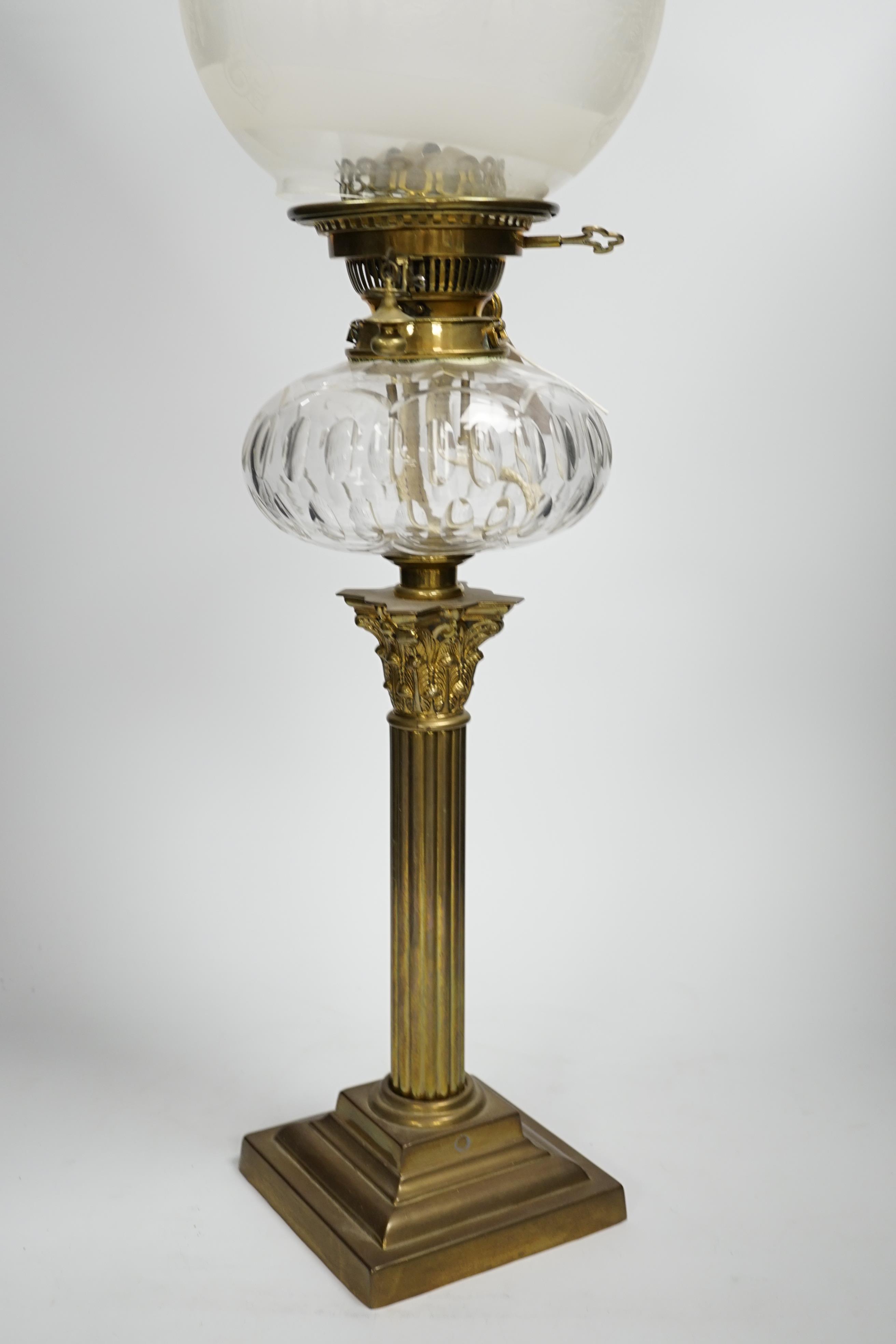 A Victorian brass oil lamp with glass reservoir and etched shade, 70cm high